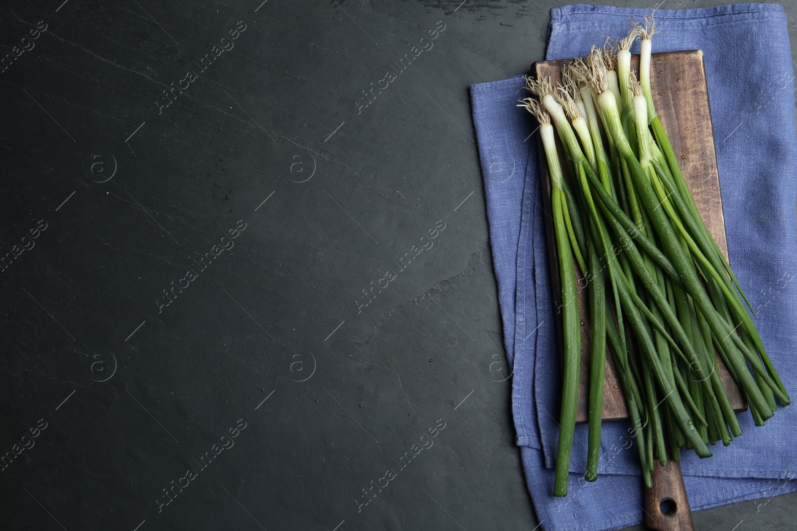 Photo of Fresh green spring onions on black table, flat lay. Space for text