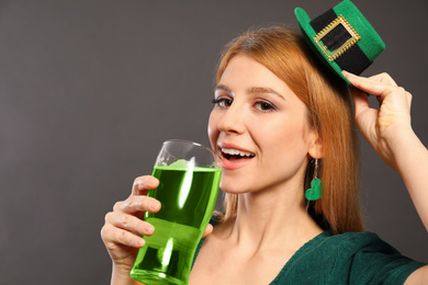 Photo of Young woman with green beer on grey background. St. Patrick's Day celebration