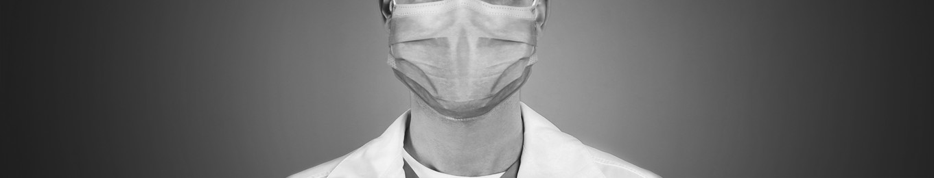 Image of Closeup view of man wearing medical face mask on grey background, banner design. Black and white photography