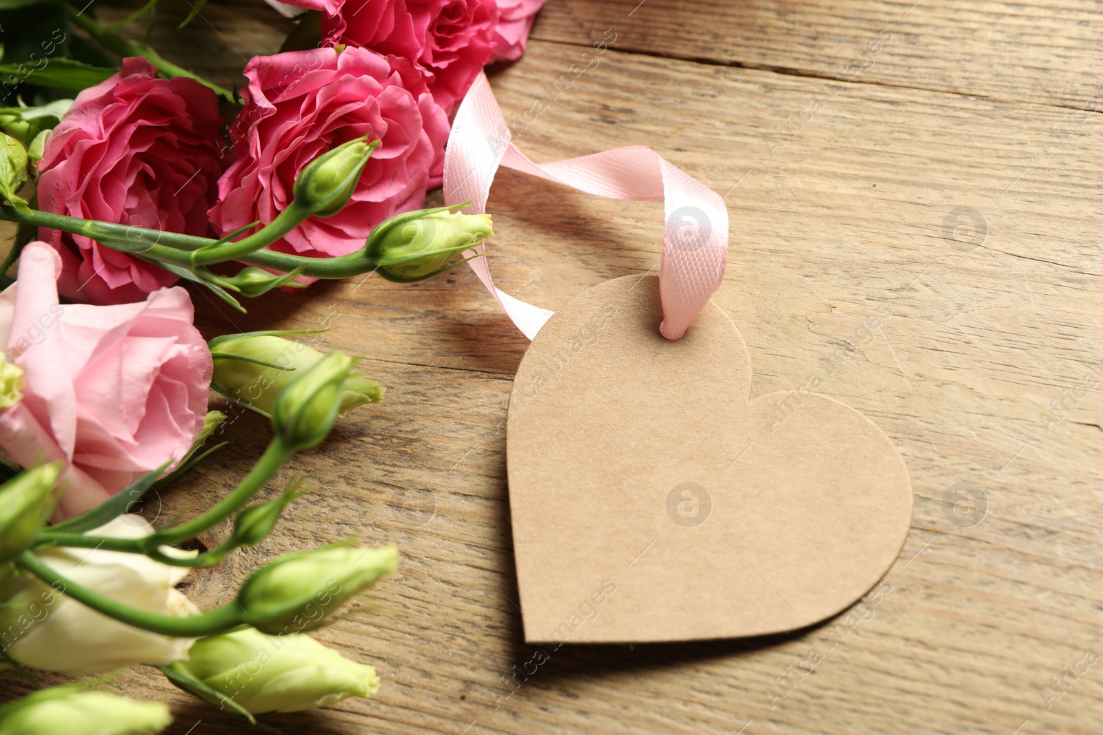 Photo of Happy Mother's Day. Beautiful flowers with blank heart shaped card on wooden table, closeup