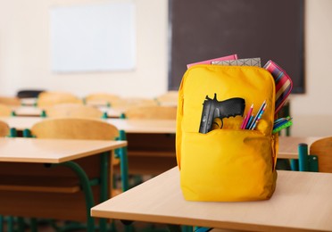 Image of School shooting. Backpack with gun and stationery in classroom