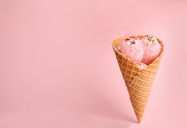 Photo of Delicious ice cream in wafer cone on pink background. Space for text