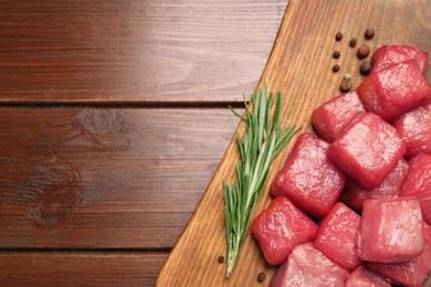 Photo of Cooking delicious goulash. Raw beef meat and rosemary on wooden table, top view with space for text