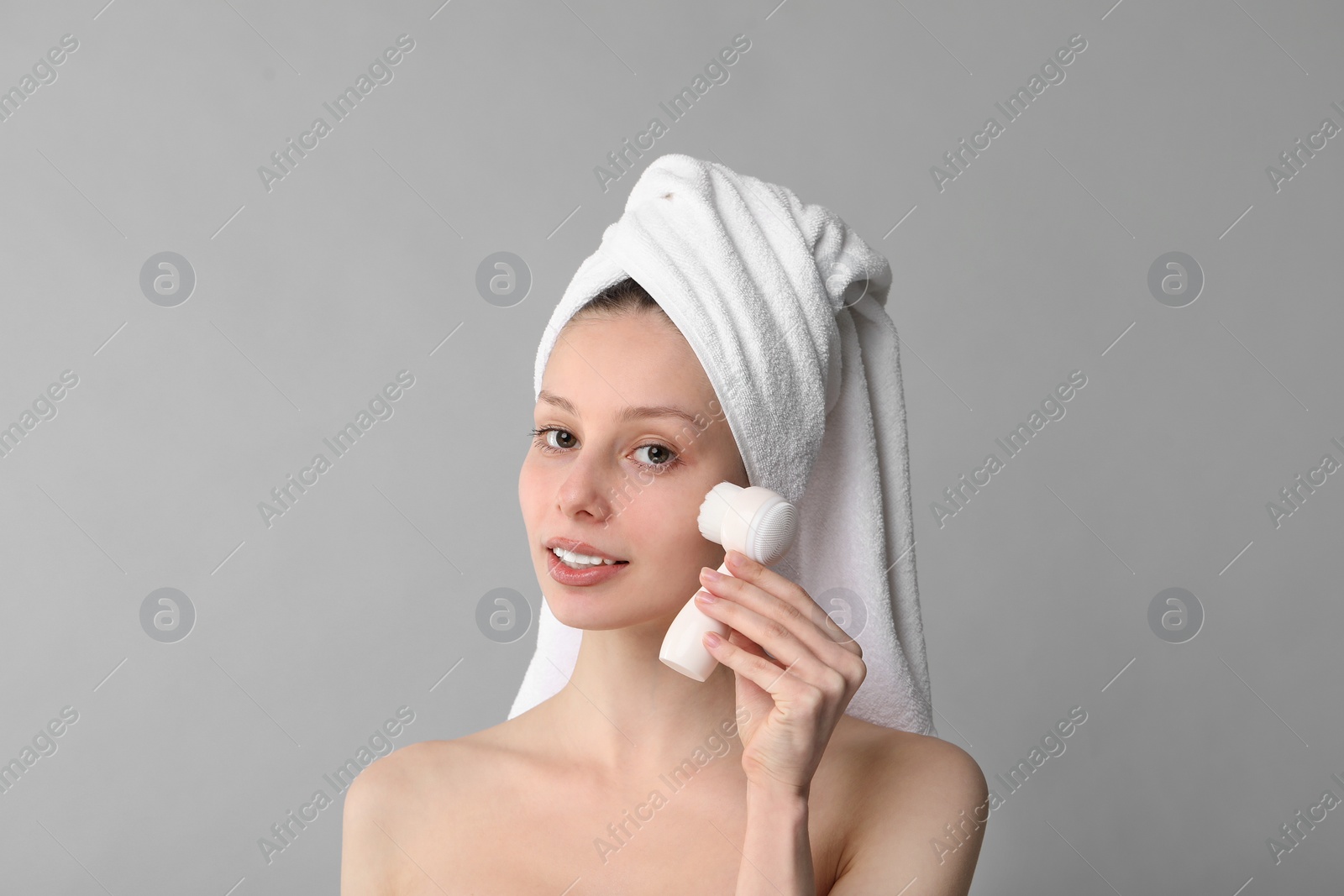 Photo of Washing face. Young woman with cleansing brush on grey background