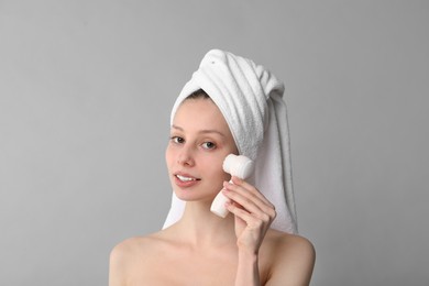 Photo of Washing face. Young woman with cleansing brush on grey background