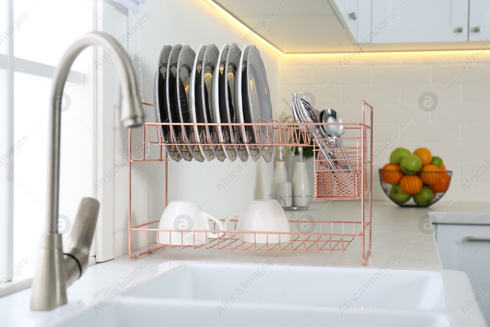 Photo of Clean dishes on drying rack in modern kitchen interior