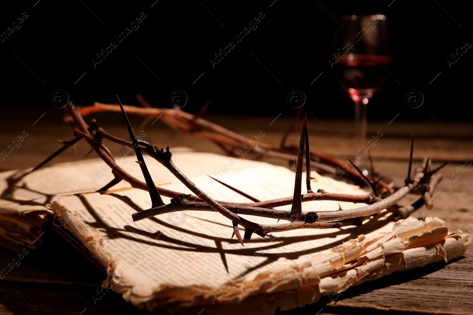 Photo of Crown of thorns and Bible on wooden table, closeup