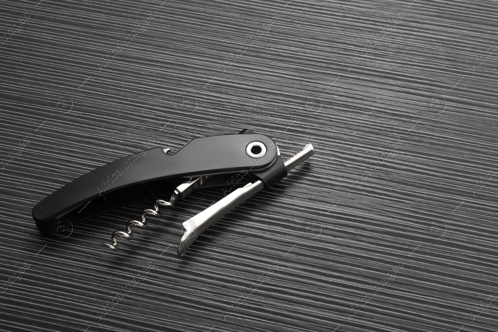 Photo of One corkscrew (sommelier knife) on black wooden table, top view. Space for text