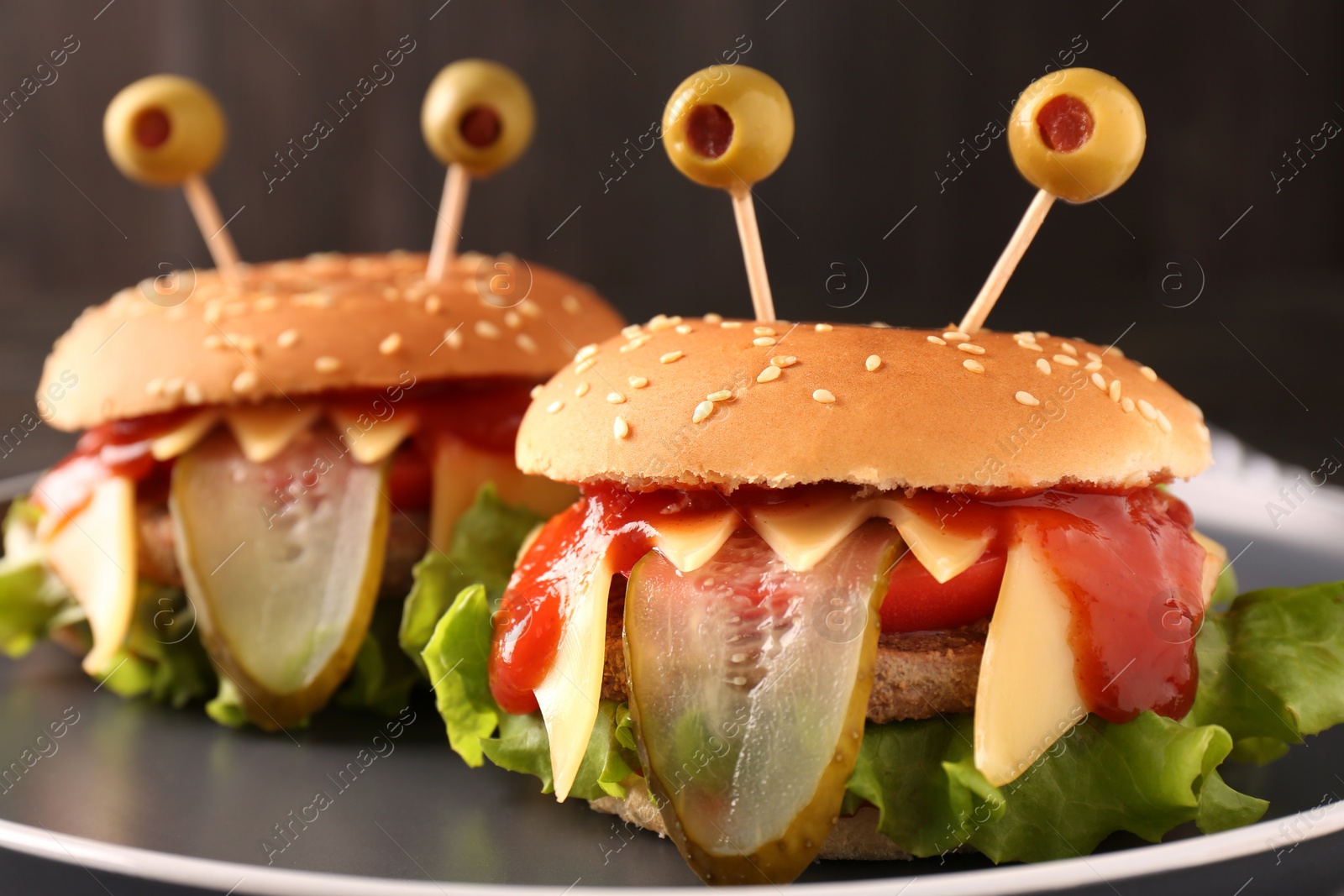 Photo of Cute monster burgers on plate, closeup. Halloween party food