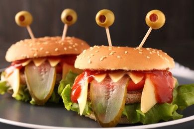 Cute monster burgers on plate, closeup. Halloween party food