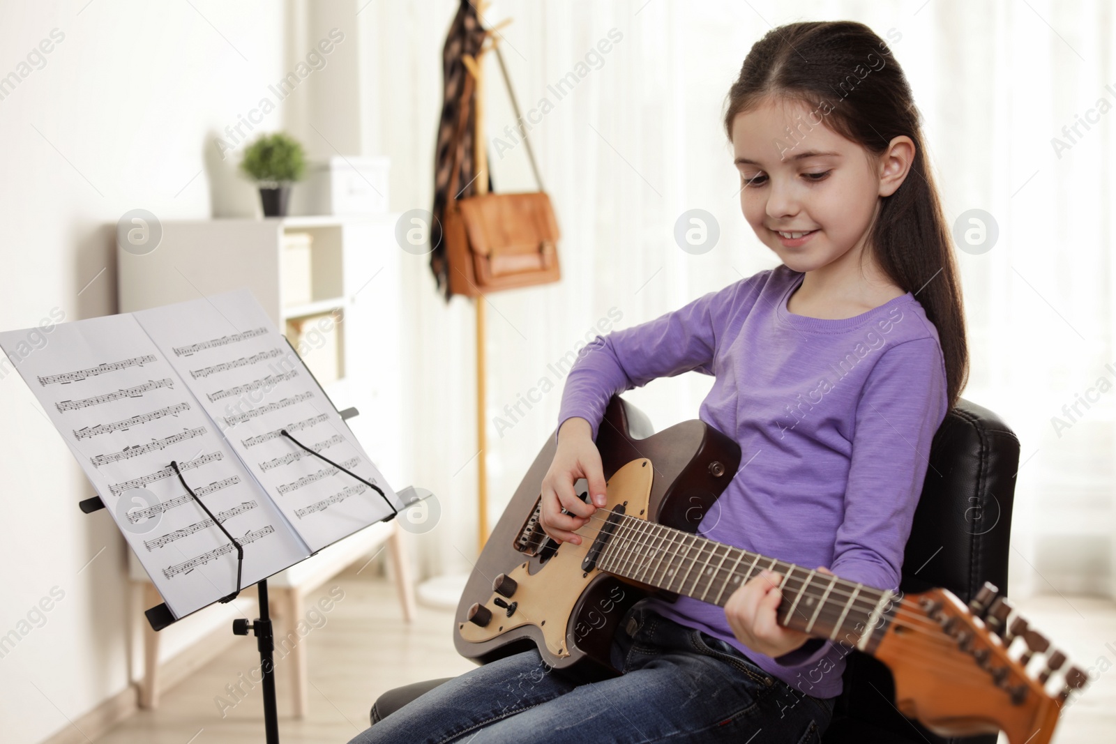 Photo of Little girl playing guitar at music lesson. Learning notes