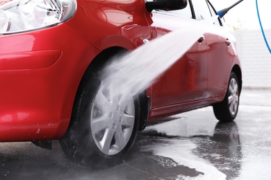 Cleaning auto with high pressure water jet at car wash, closeup