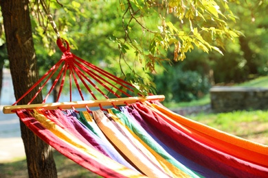 Photo of Bright comfortable hammock hanging in green garden, closeup