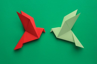 Photo of Beautiful colorful origami birds on green background, flat lay