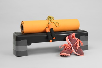 Step platform, yoga mat, skipping rope and sneakers on light background. Sport equipment