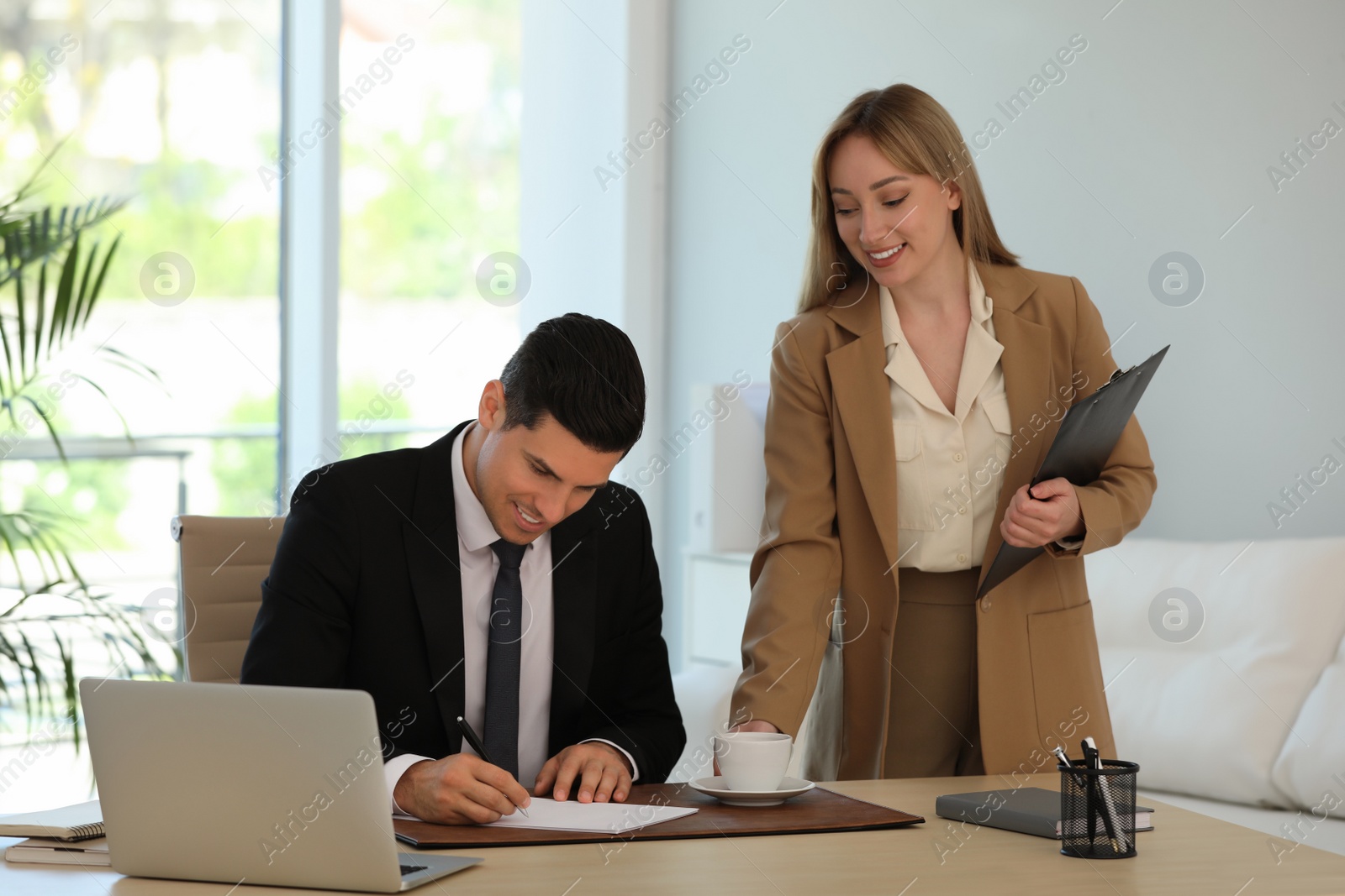 Photo of Secretary bringing coffee to her boss in office