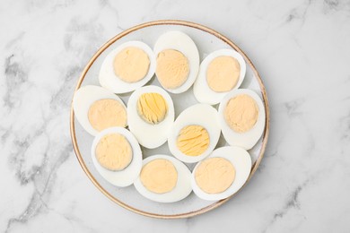 Photo of Fresh hard boiled eggs on white marble table, top view