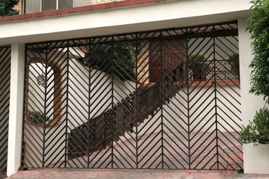 Photo of Closed metal gates near beautiful house on city street