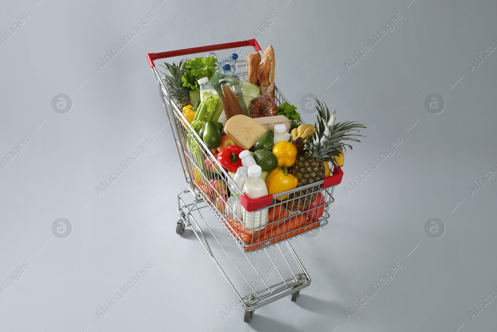 Photo of Shopping cart full of groceries on grey background