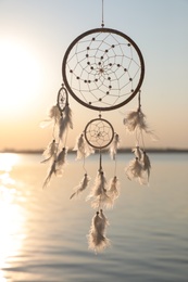 Photo of Beautiful handmade dream catcher near river at sunset