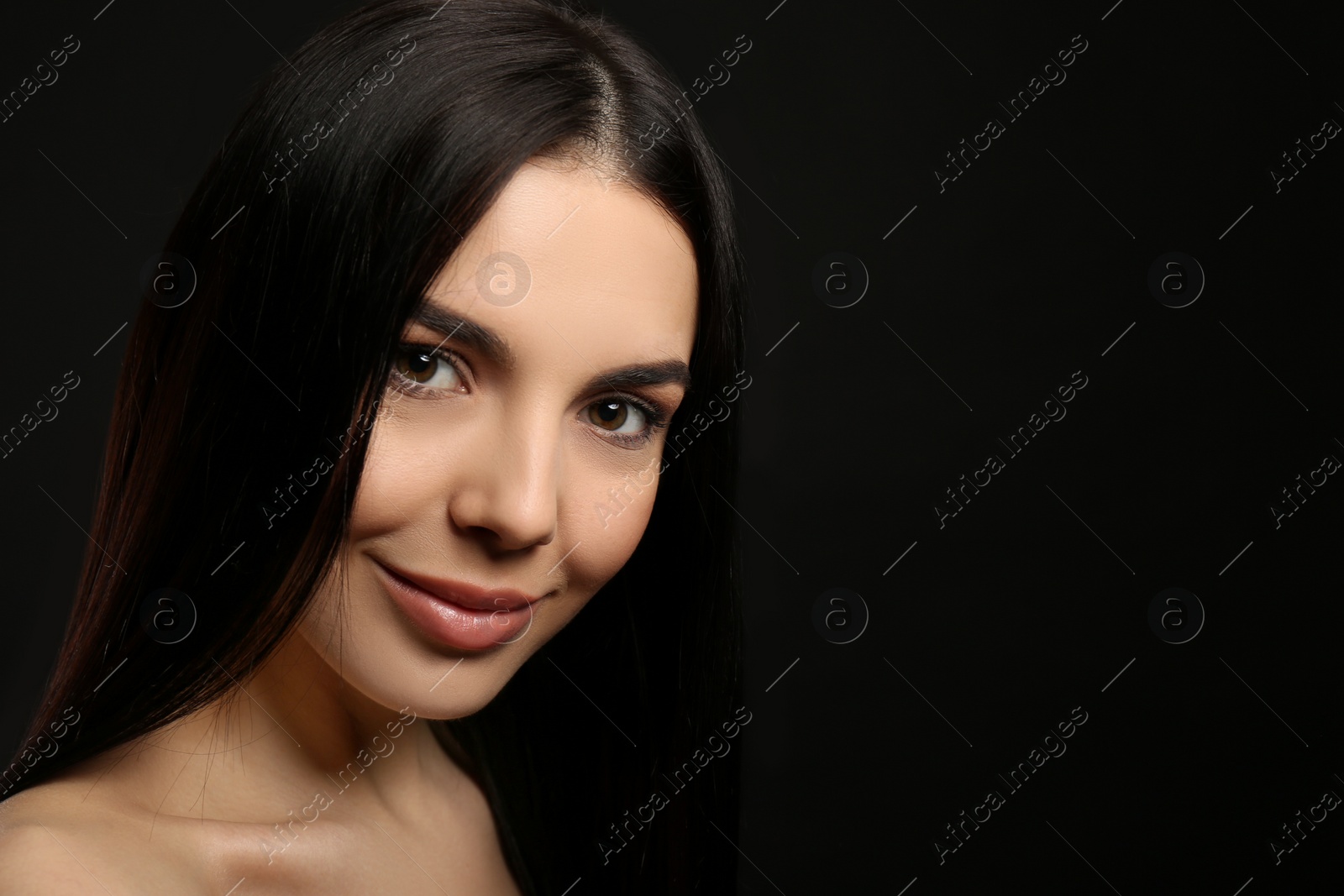 Photo of Portrait of happy young woman with beautiful black hair and charming smile on dark background, space for text