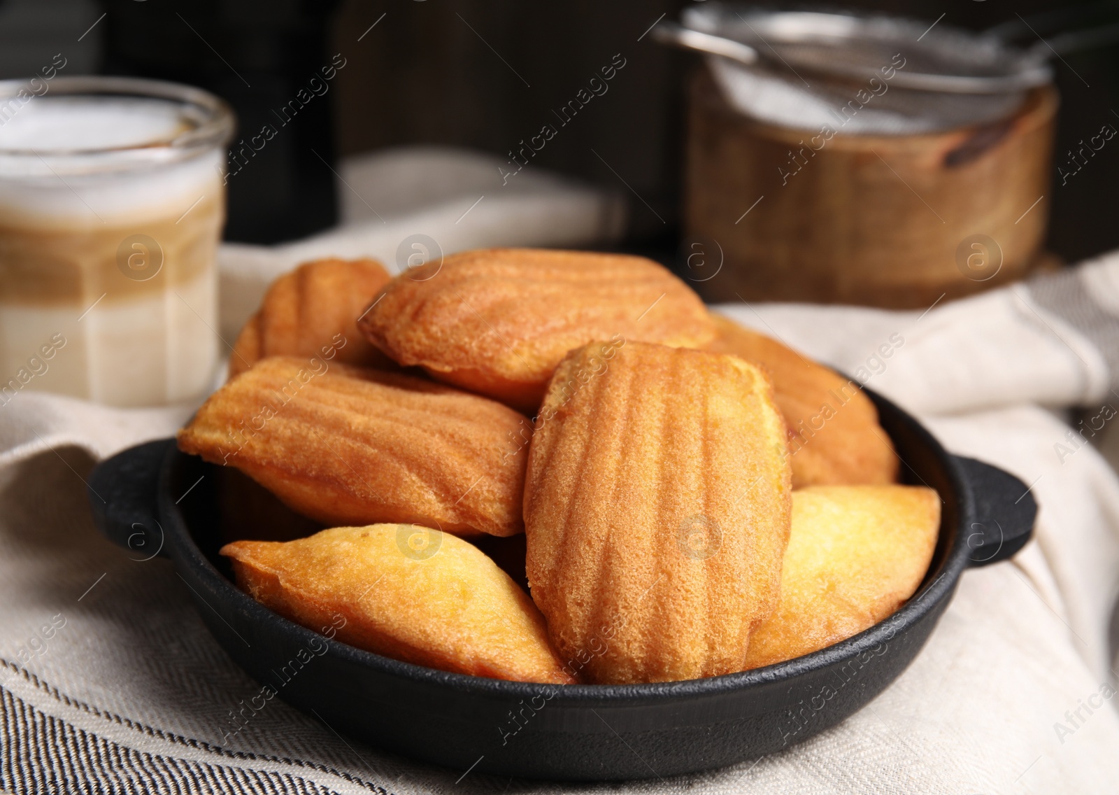 Photo of Delicious madeleine cakes in frying pan on table, closeup