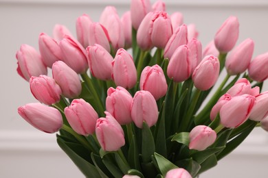 Bouquet of beautiful pink tulips near white wall, closeup