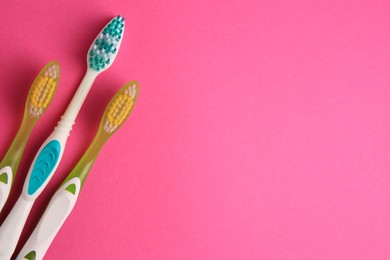 Toothbrushes on pink background, flat lay. Space for text