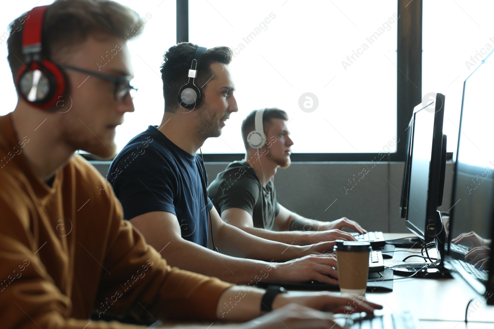 Photo of Men playing video games in internet cafe