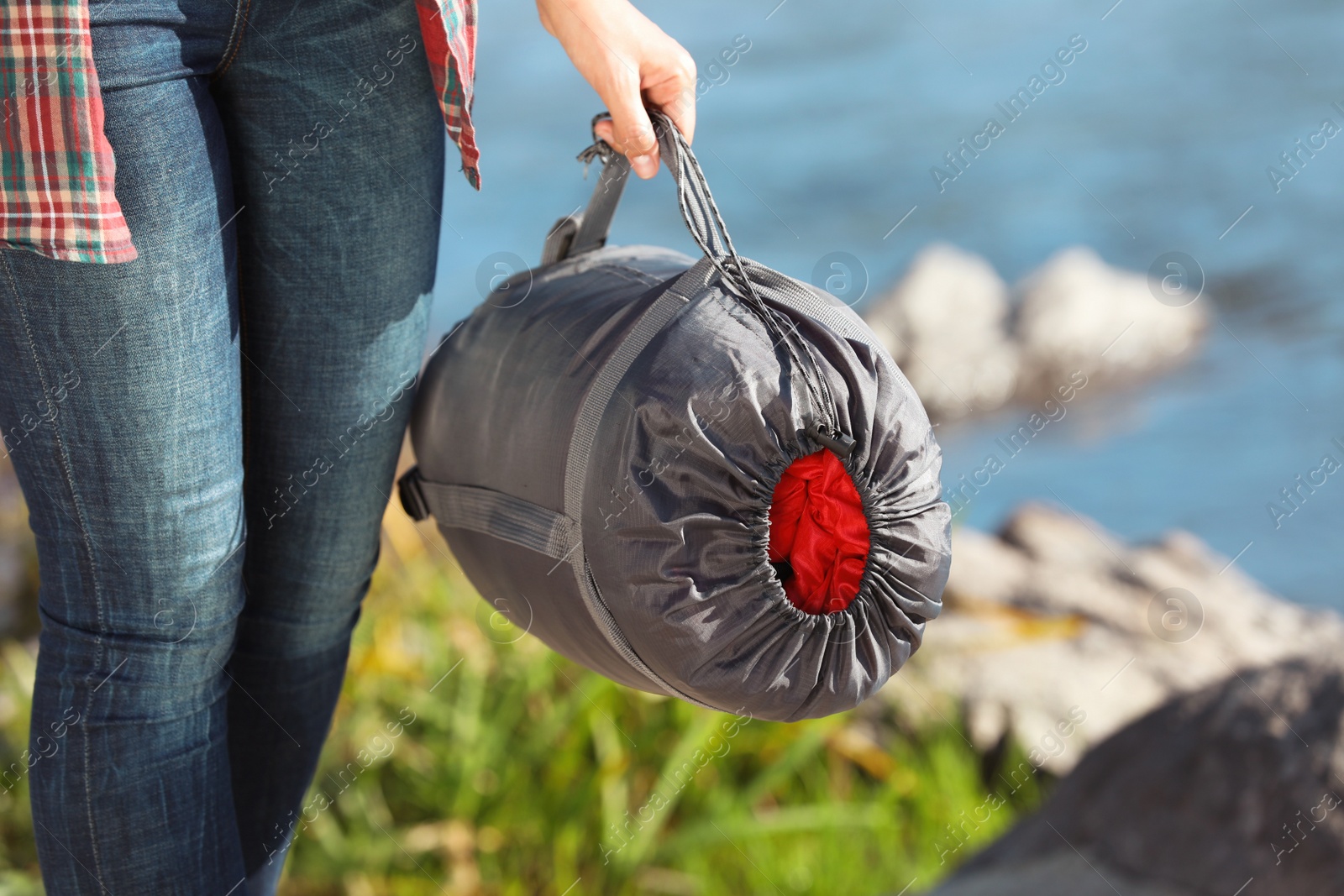 Photo of Female camper with sleeping bag outdoors, closeup. Space for text