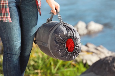 Female camper with sleeping bag outdoors, closeup. Space for text