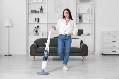 Photo of Happy woman cleaning floor with steam mop at home