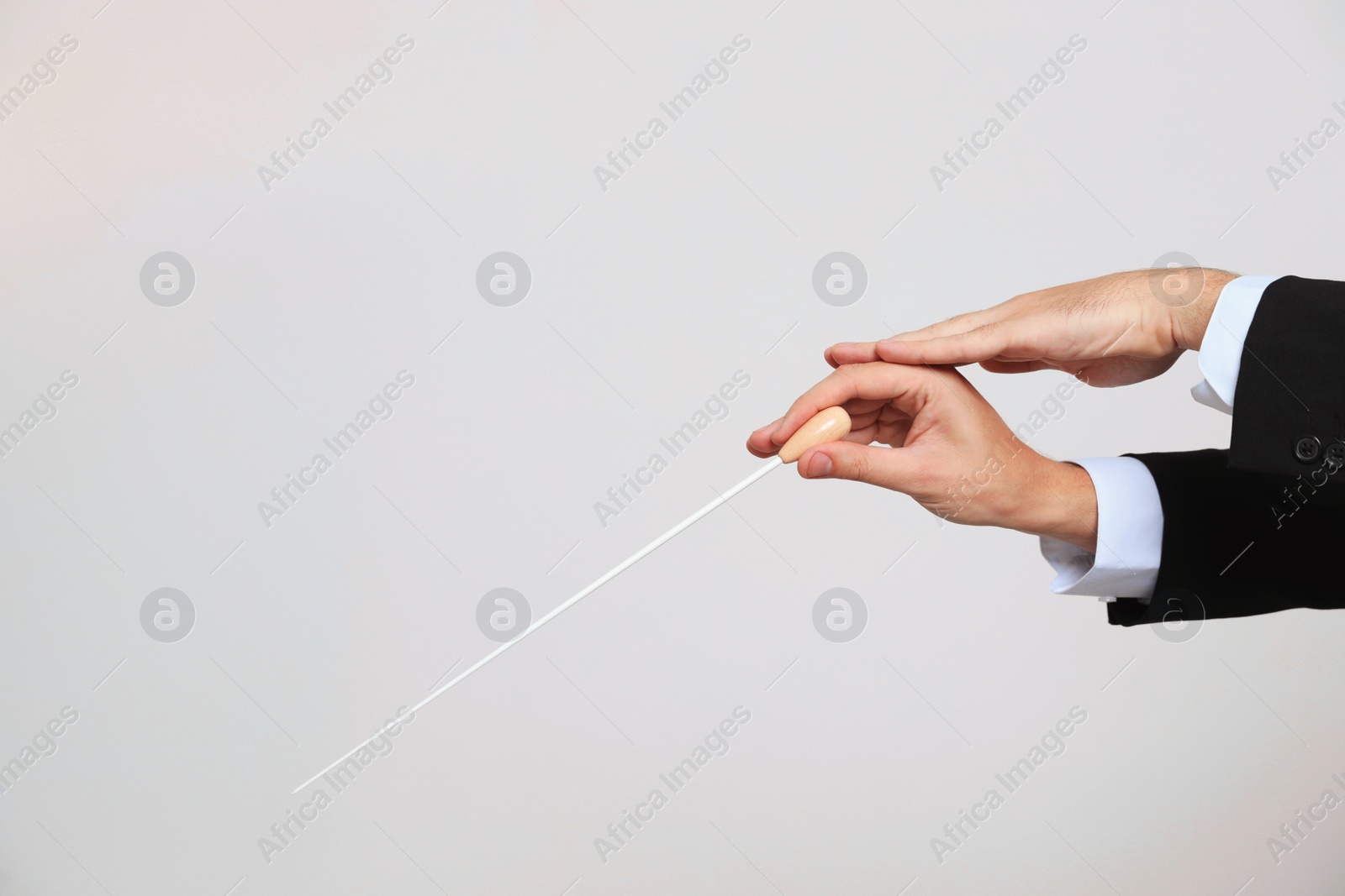 Photo of Professional conductor with baton on light grey background, closeup. Space for text