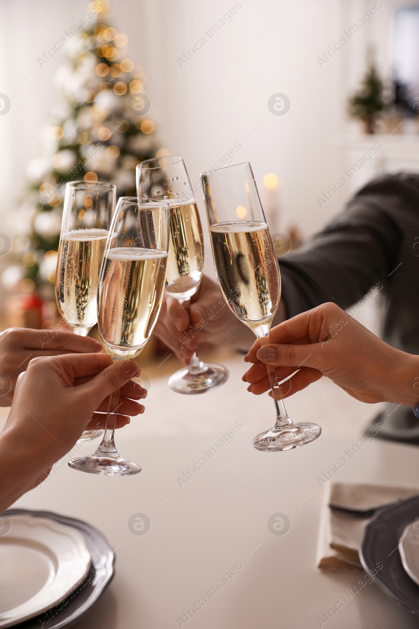 Photo of People clinking glasses with champagne at home, closeup