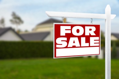 Image of Sale sign near beautiful house outdoors. Red signboard with words