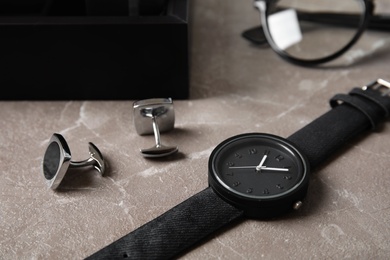 Photo of Stylish wrist watch and cuff links on table. Fashion accessory