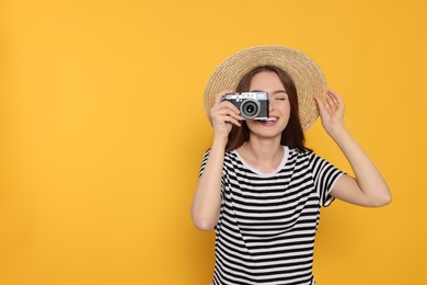 Photo of Young woman with camera taking photo on yellow background, space for text. Interesting hobby