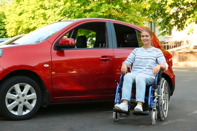 Young woman in wheelchair near car outdoors