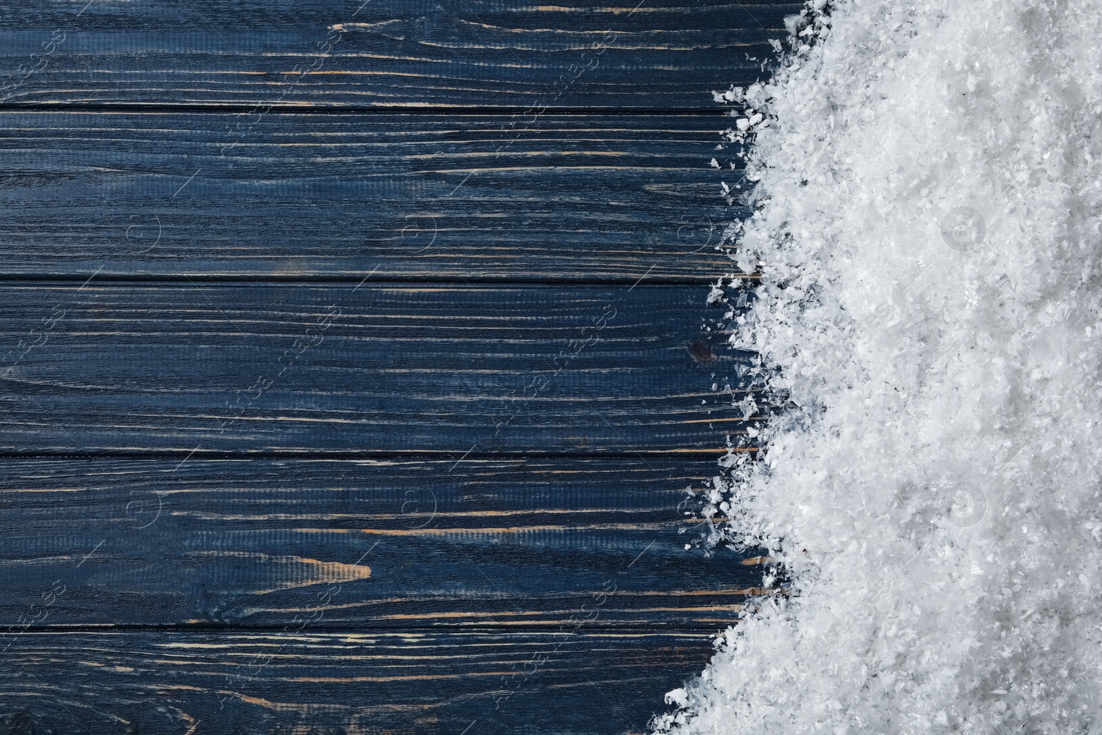 Photo of Snow and space for text on blue wooden background, top view. Christmas time