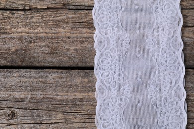 Photo of White lace on wooden table, top view. Space for text