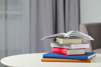 Stack of hardcover books on white table indoors, space for text