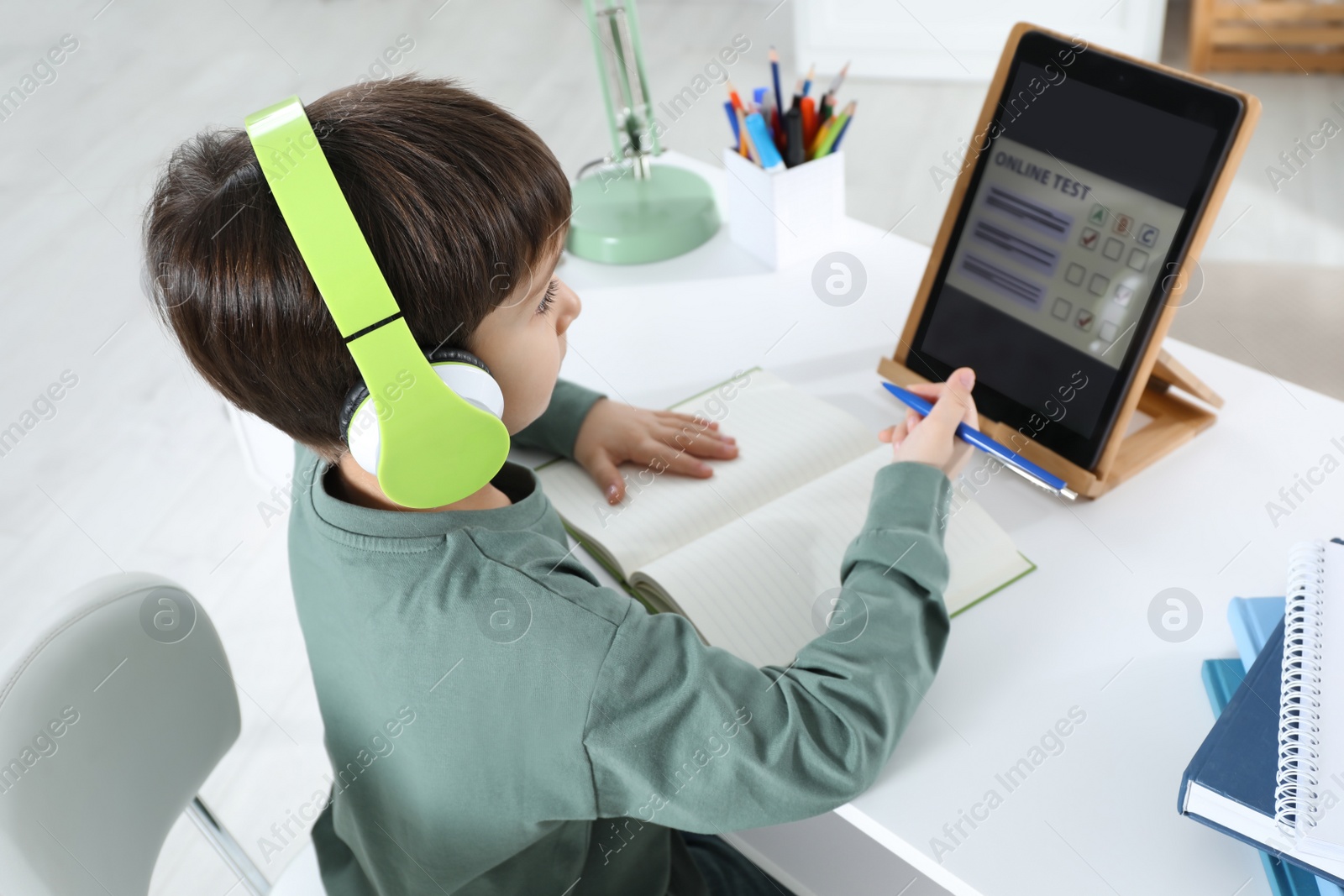 Photo of Cute little boy with modern tablet studying online at home. E-learning