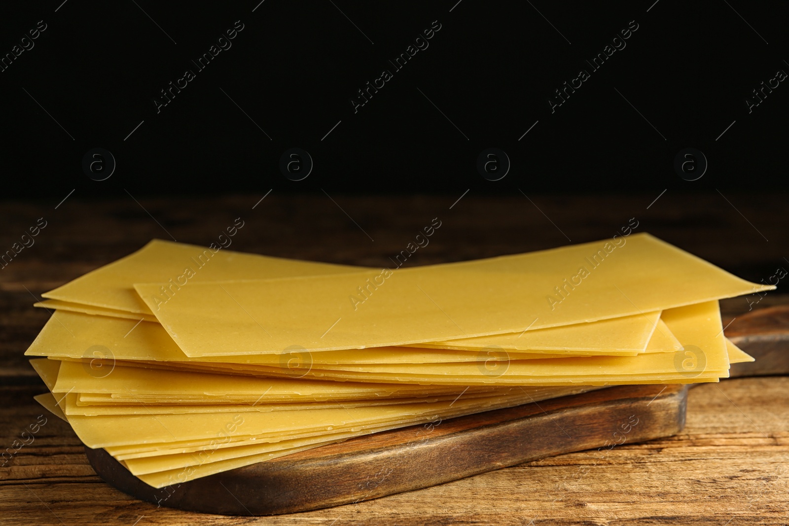 Photo of Uncooked lasagna sheets on wooden table, closeup