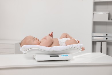 Photo of Cute little baby lying on scales in clinic