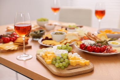 Photo of Assorted appetizers and rose wine served on wooden table, selective focus. Space for text