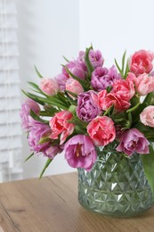 Photo of Beautiful bouquet of colorful tulip flowers on wooden table indoors