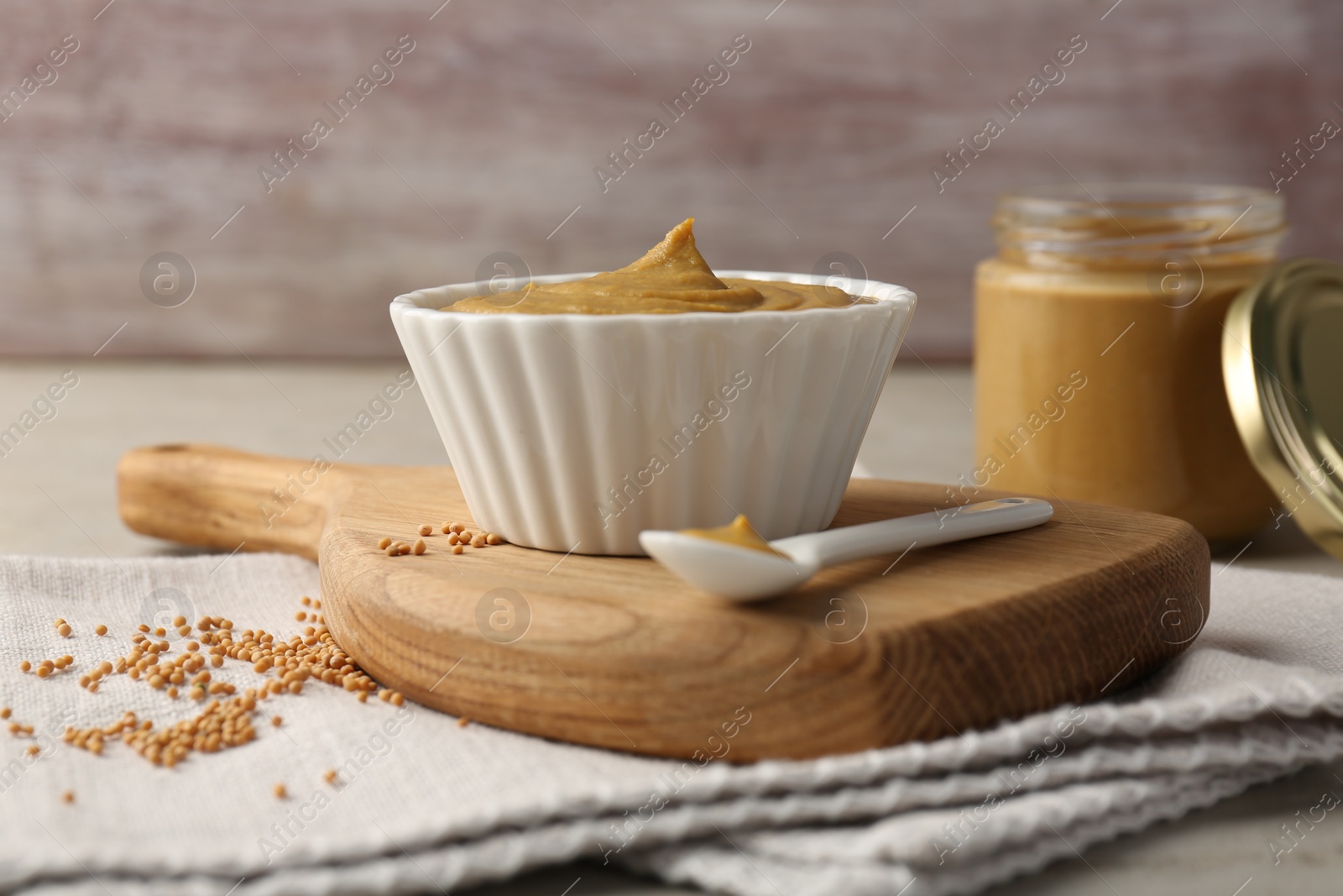 Photo of Tasty mustard sauce and dry seeds on light table