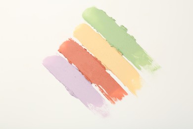 Photo of Samples of different color correcting concealers on white background, top view