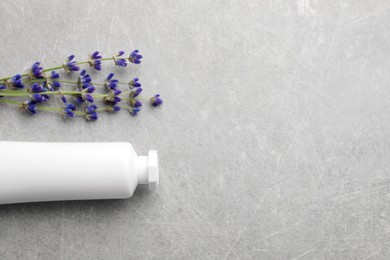 Photo of Tube of hand cream and lavender on light grey table, flat lay. Space for text
