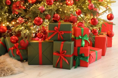 Photo of Many gift boxes under decorated Christmas tree indoors